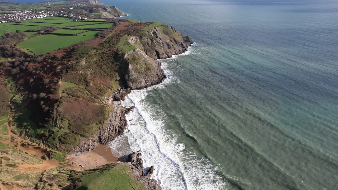 Side angle aerial movement over Pobbles Bay with cliffs beach and ocean unfolding along the Gower Peninsula coast in Wales