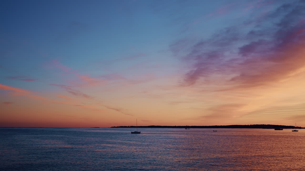 Beautiful sunset sky in warm shades of orange, pink, and purple above a calm coastline in the French Riviera