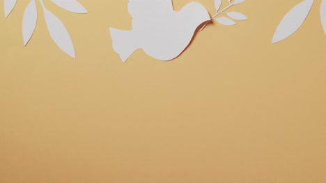 close up of white dove with leaves and copy space on yellow background