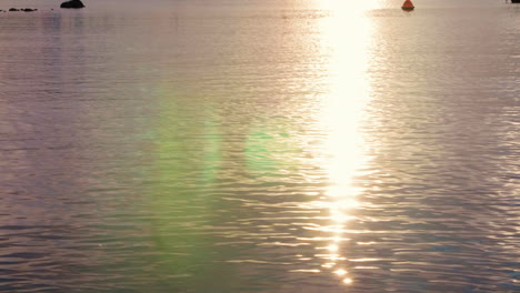 Calm-shimmering-water-tilts-up-to-gorgeous-city-during-early-morning-golden-hour