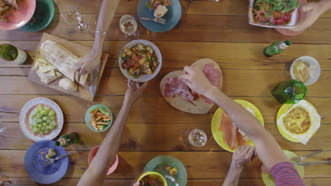amigos pasando comida alrededor de una mesa de cena, por encima, filmado en r3d