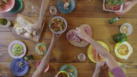 friends passing food around a dinner table, overhead, shot on r3d