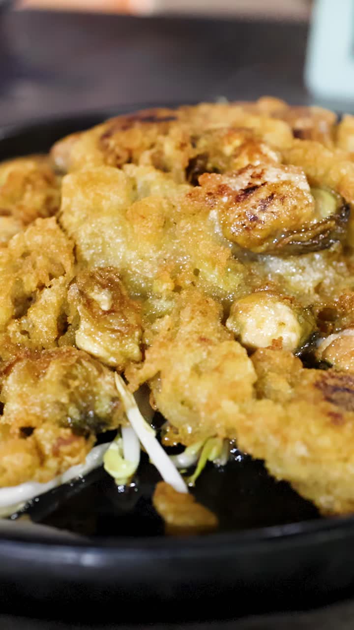 Frittella di ostriche dorata sfrigola su piastra calda, primo piano, profondità di campo ridotta, atmosfera vibrante di street food.