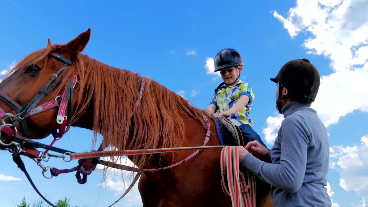 niño con casco sentado en el caballo y agitando la mano