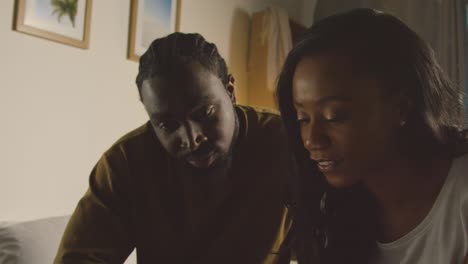 Young-Couple-Relaxing-At-Home-At-Night-In-Bedroom-Looking-At-Mobile-Phone-Together-2