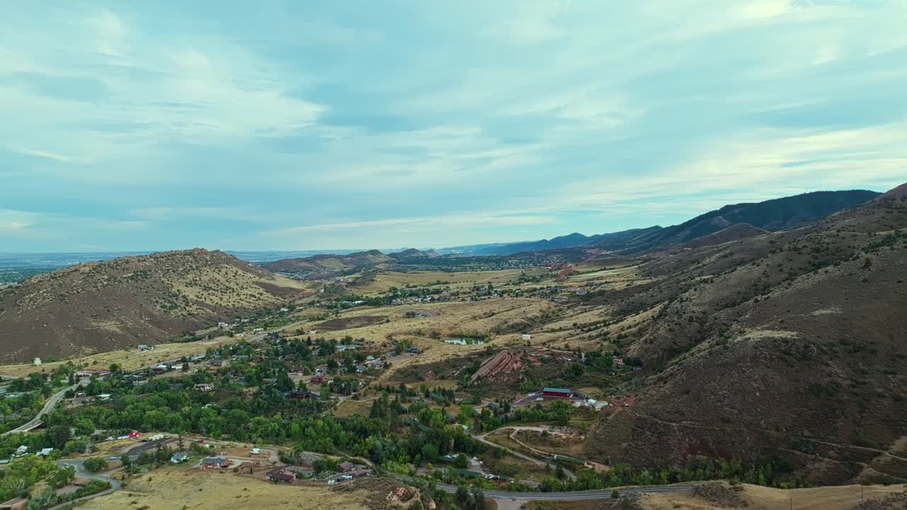Panoramic establishing of Red Rocks Amphitheatre structure surrounded by dramatic red cliffs and blue Colorado sky
