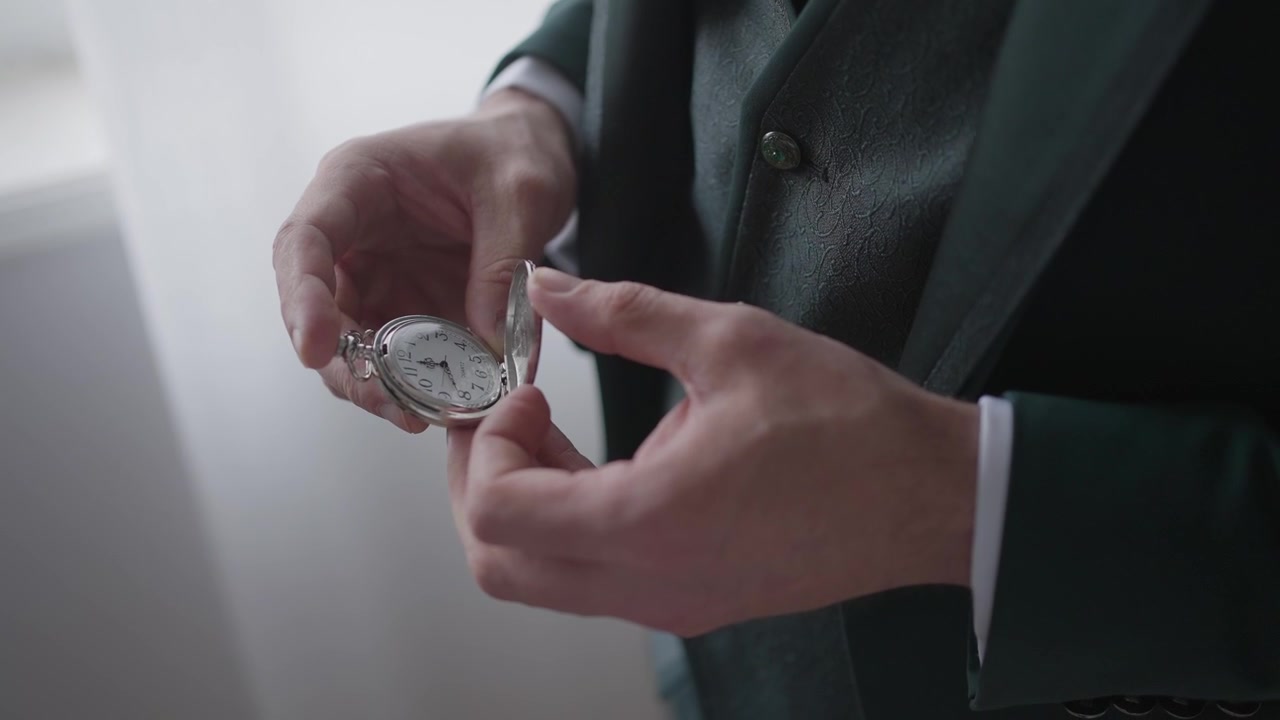 Close view of hands opening vintage pocket watch while dressed in formal attire