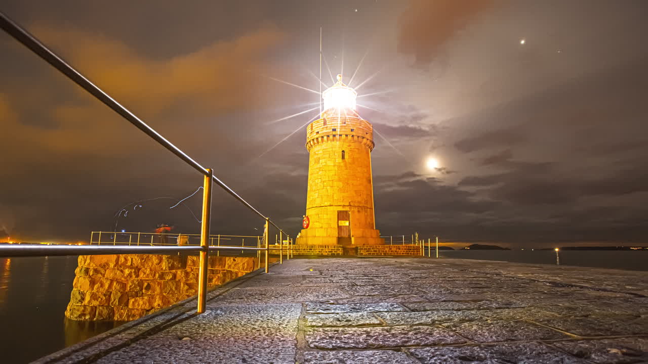 Castle Lighthouse Illuminated With Moon Over Cloudy Evening Sky At Saint Peter Port, Guernsey