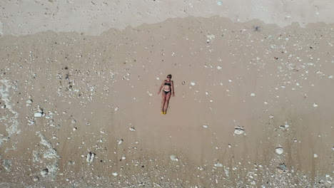 Beautiful-girl-lie-down-on-beach-and-drone-top-view-bird's-eye-perspective