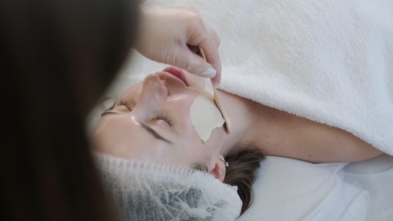 미용 전문가가 얼굴 치료와 얼굴 마스크를 적용합니다.