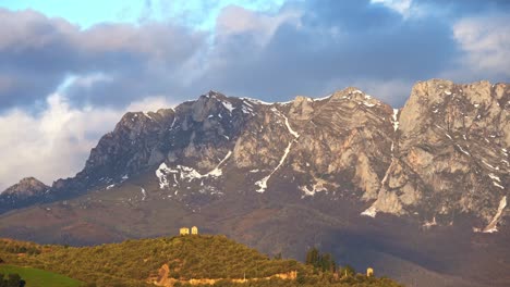 Mountain-ridge-with-trees-under-cloudy-sky