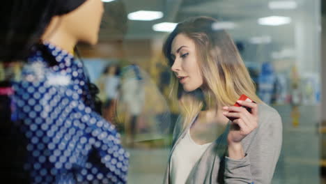 attractive woman ready for shopping examines the shop window holding a card for purchases she carrie