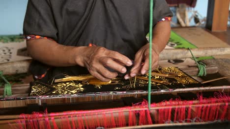 woman weaving on a back-strap loom