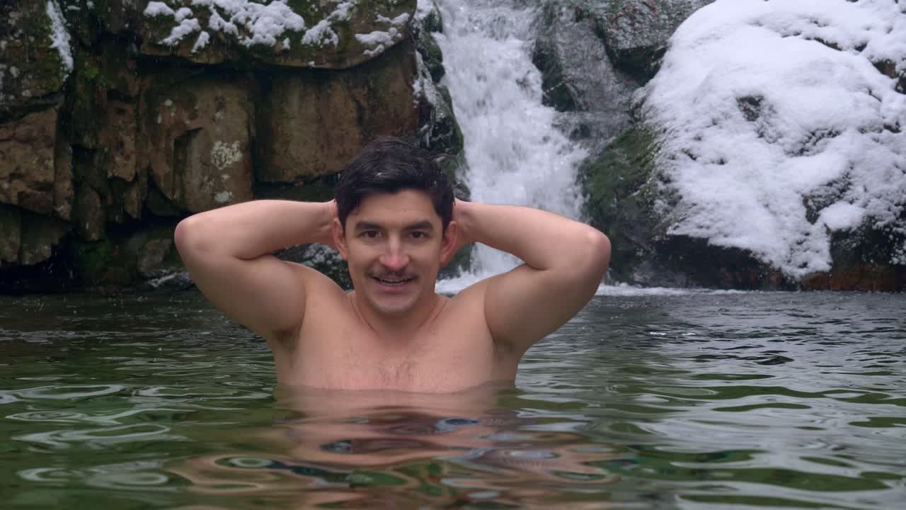 용감한 남자는 겨울날 눈 덮인 산의 장엄한 폭포 옆에서 찬물에 뛰어든다 - 정적 샷, 느린 동작