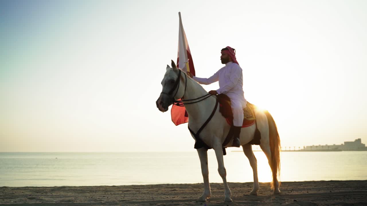 un caballero a caballo sosteniendo la bandera de qatar cerca del mar-1