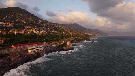 mediterranean coast during sunset, beautiful aerial view, waves hit rocky shore, golden light falls on houses, peaceful nature and village scenes