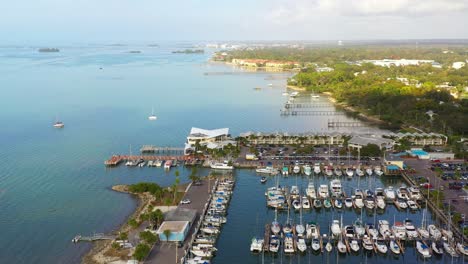 Drone-footage-over-downtown-Dunedin,-Florida-marina-with-boats-and-the-Gulf-of-Mexico-and-Tampa-Bay