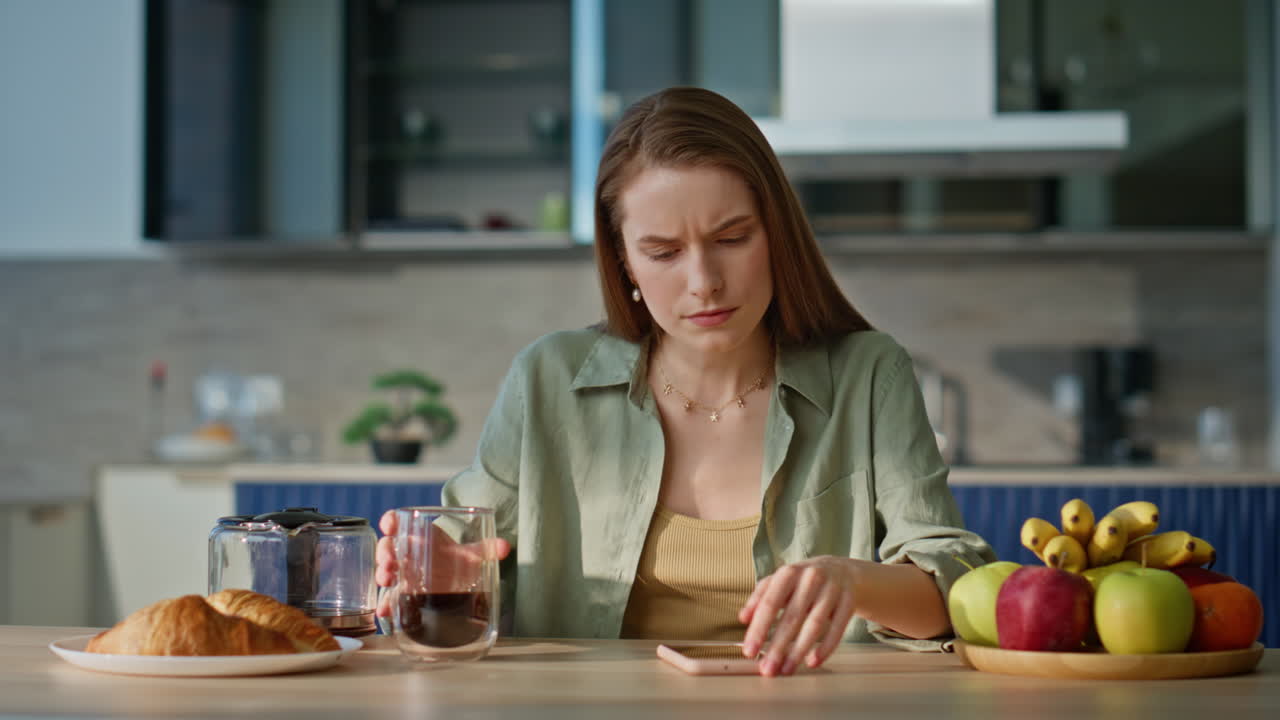 Home woman sipping coffee at breakfast receiving cellphone message closeup