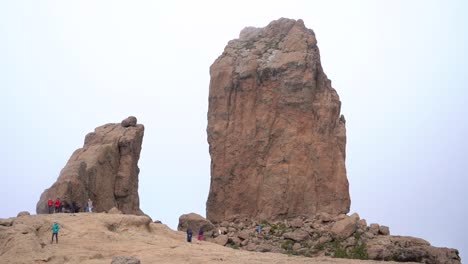 grupo de senderismo ascendiendo al roque nublo duroing una mañana brumosa en la isla de gran canaria, españa