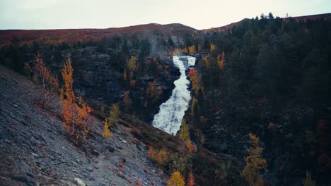 waterfall flowing down through rocky mountains in dovrefjell, norway during autumn