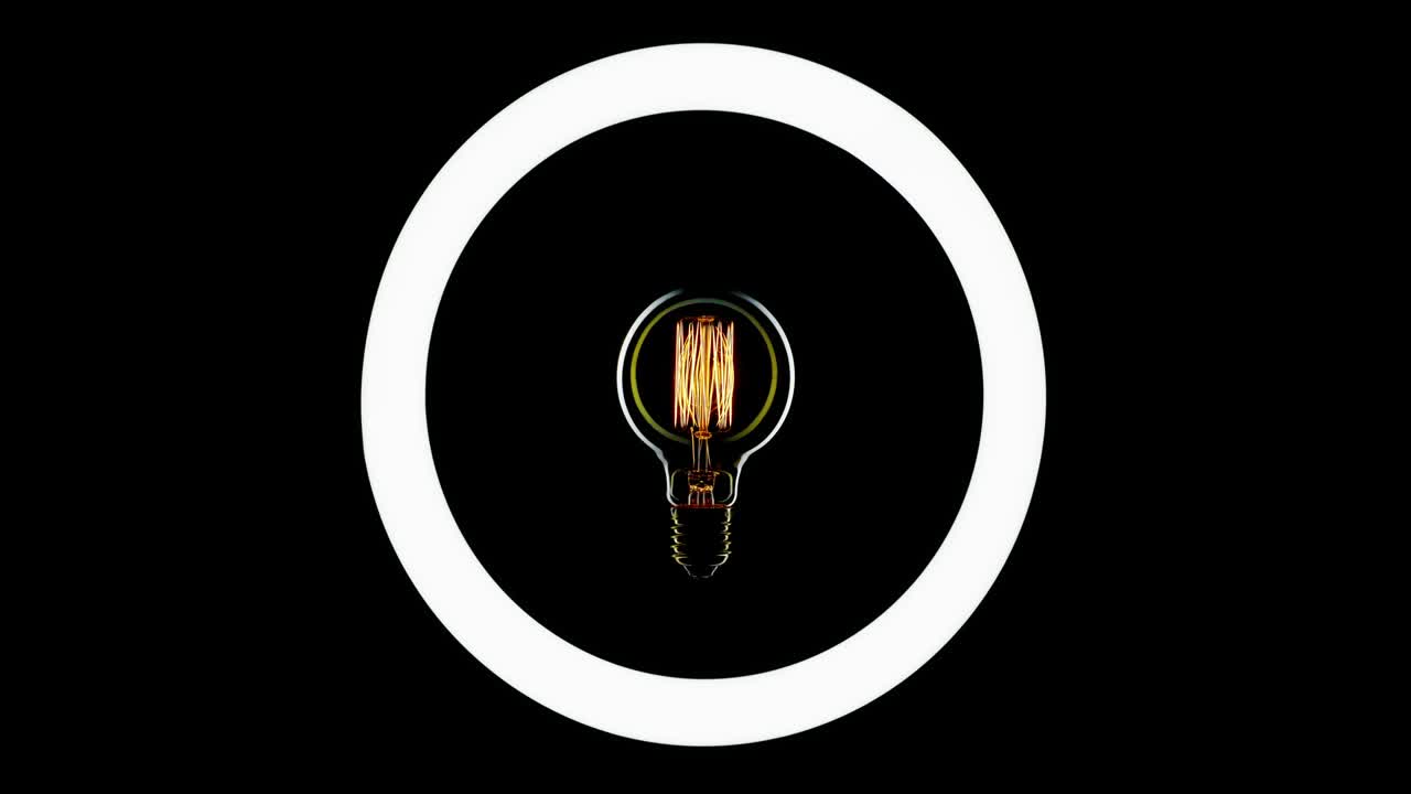 Tungsten light bulb blinking over black background.