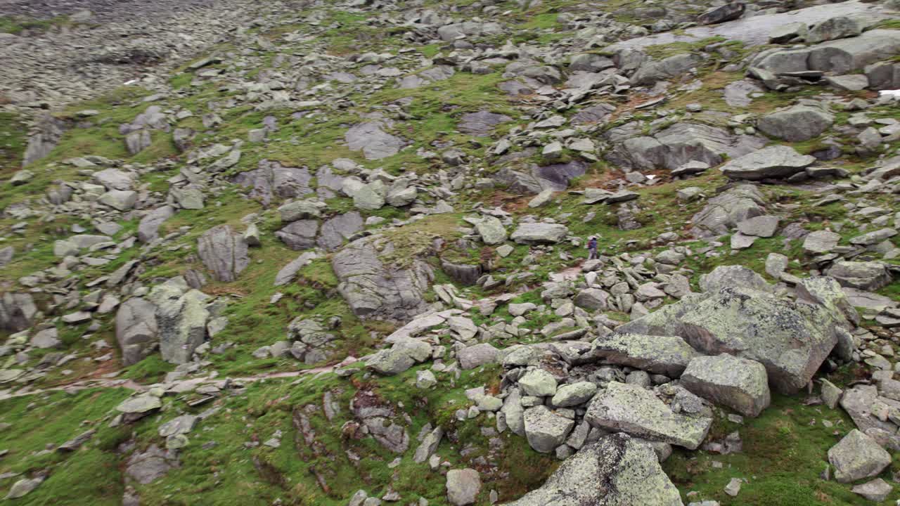 Panoramica aerea 4K con drone di un'escursionista verso il ghiacciaio dell'Aletsch, ghiaccio strutturato e crepacci che scorrono attraverso un'alta valle alpina sotto cieli coperti nelle Alpi Svizzere