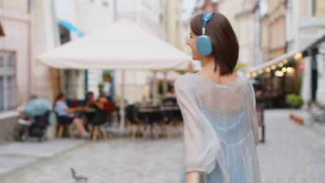 Rear view of young woman tourist walking through the street outdoors looking searching for a way