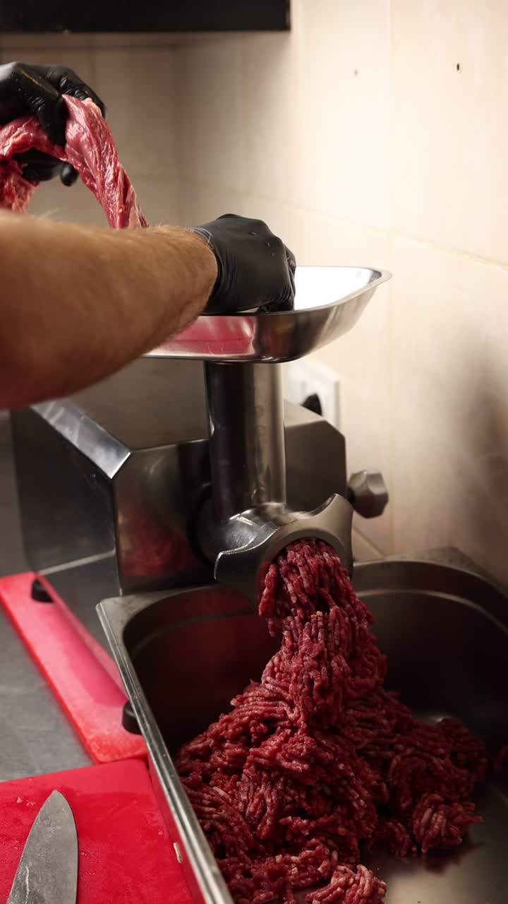 Chef hachant de la viande crue dans une cuisine professionnelle