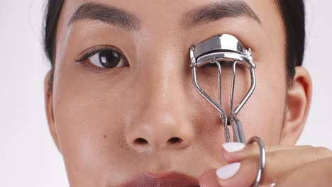 applying eyelash curler to asian woman's eye