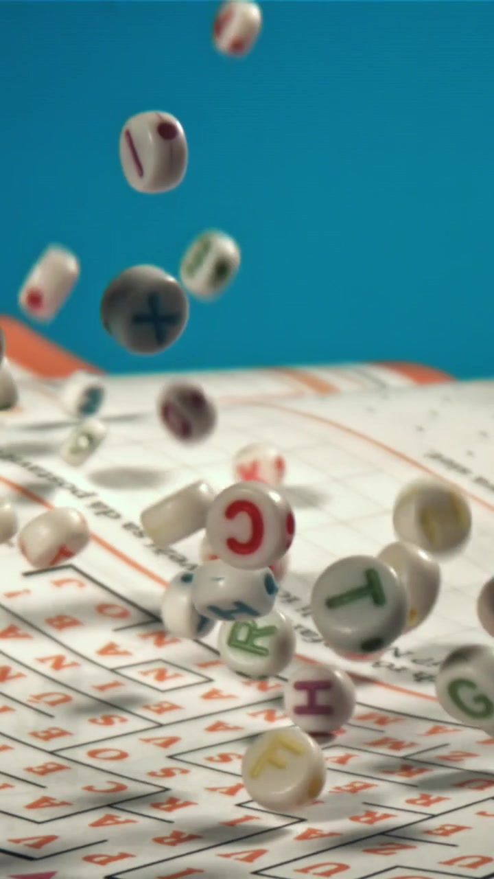 Colorful Letter Beads Falling onto a Crossword Puzzle