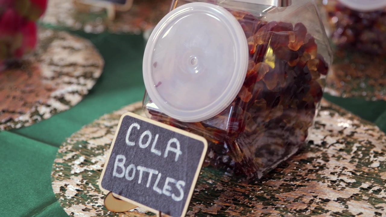 Close-up genggam toples permen botol cola di meja permen pernikahan.