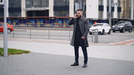 young man talks on smartphone on street. portrait of a handsome man having a phone talk outdoors. businessman talking mobile phone in the city. slow motion.