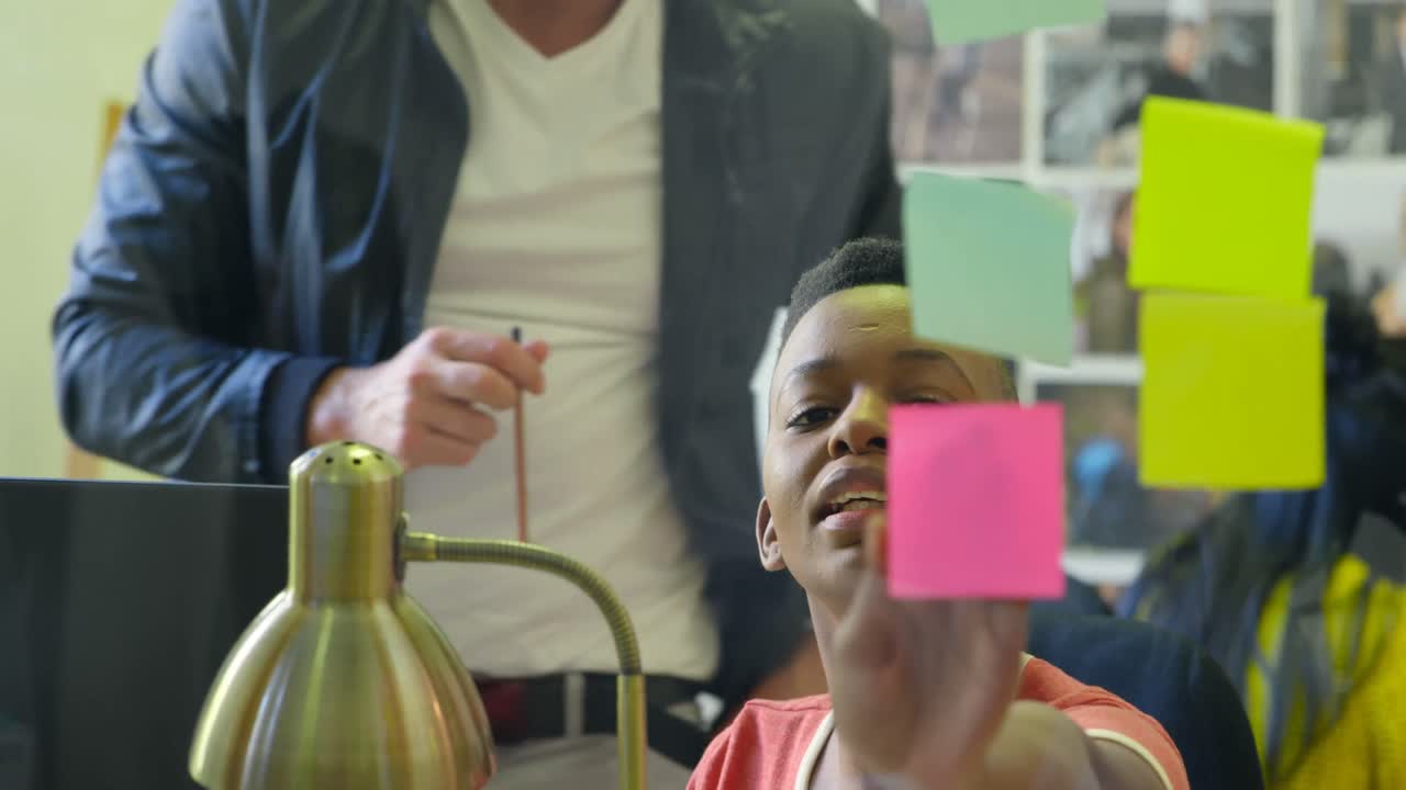 Male and female graphic designers discussing over sticky notes 4k