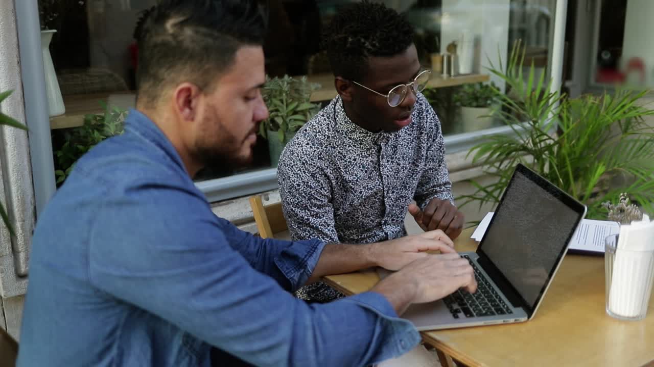 Focused young men typing and pointing on laptop