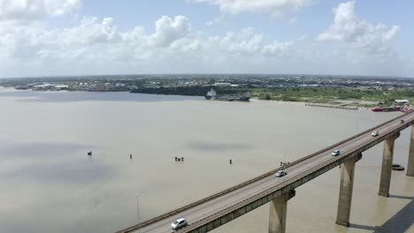 wide angle aerial shot of jules wijdenbosch bridge between paramaribo and meerzorg in suriname, south america, with heavy traffic as drone gains backwards, revealing bridge