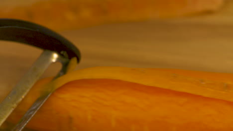 close up of a peeler cutting through the skin of a carrot