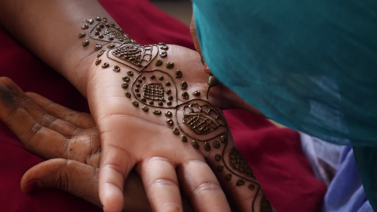 Un primo piano della mano di una donna di colore che viene dipinta con l'henné.