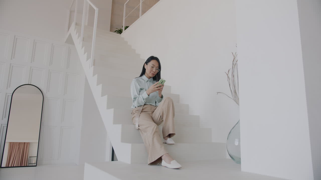 Woman using phone on stairs in a modern home