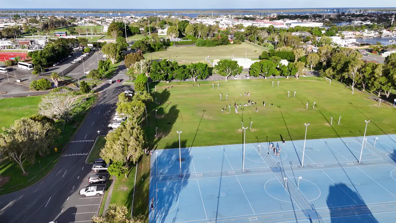 Drone footage captures netball and soccer fields with players in Gold Coast, Australia, under bright daylight