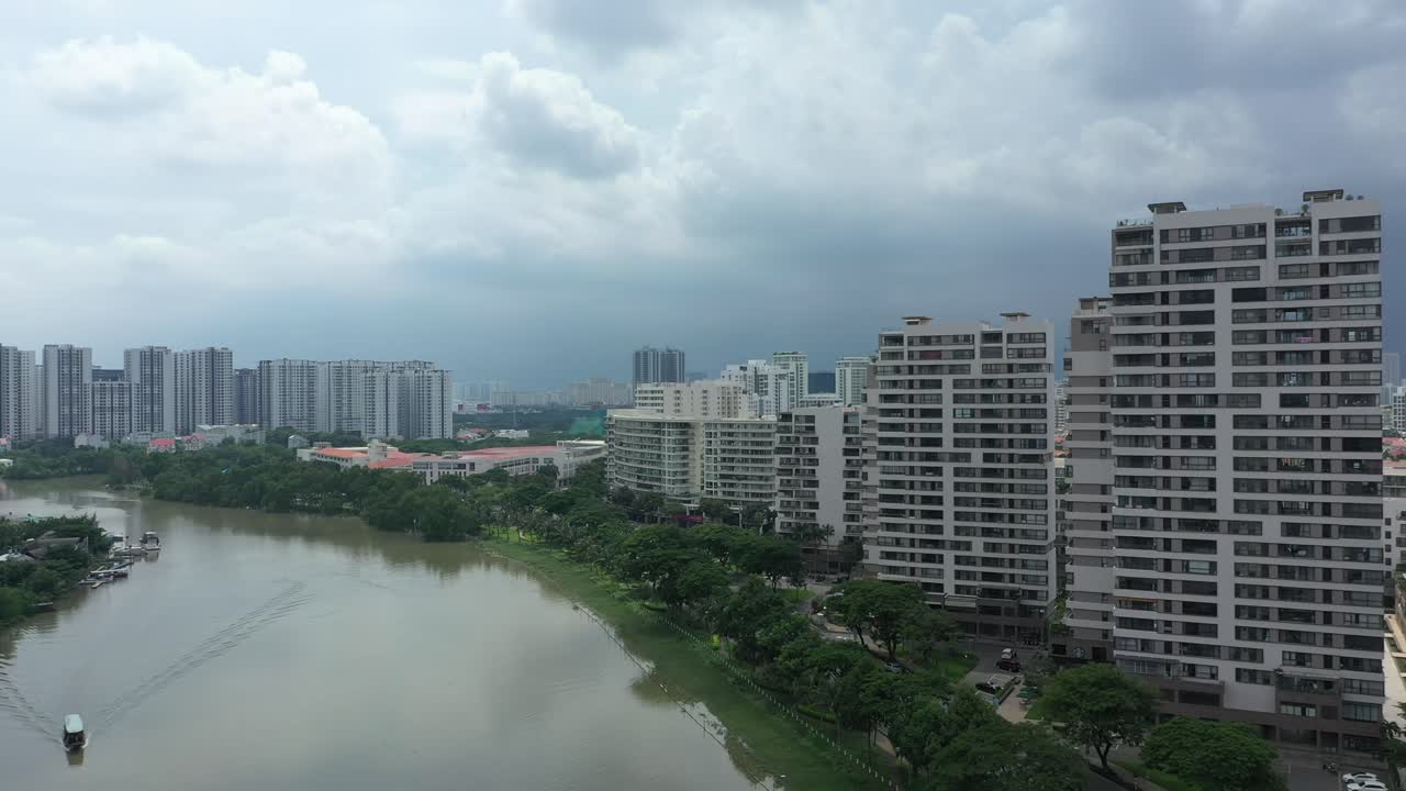 흥미로운 건축물과 도시 스카이라인을 볼 수 있는 대형 교육 기관을 특징으로 하는 초현대식 주거용 고층 개발로 강을 따라 비행하는 드론 샷