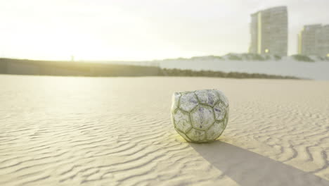 soccer ball resting on the sand during sunrise at a coastal location