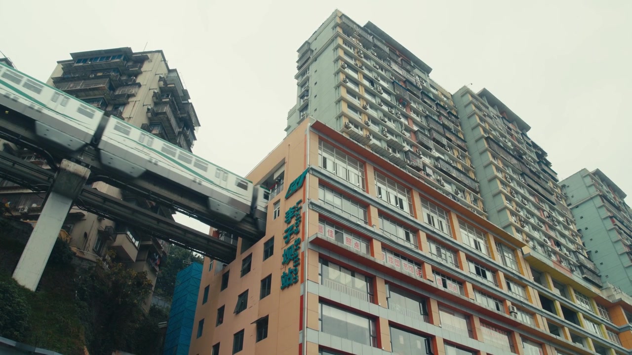 Trem Monotrilho Liziba de Chongqing Passando por Edifício Residencial Ângulo Baixo Diurno (1)
