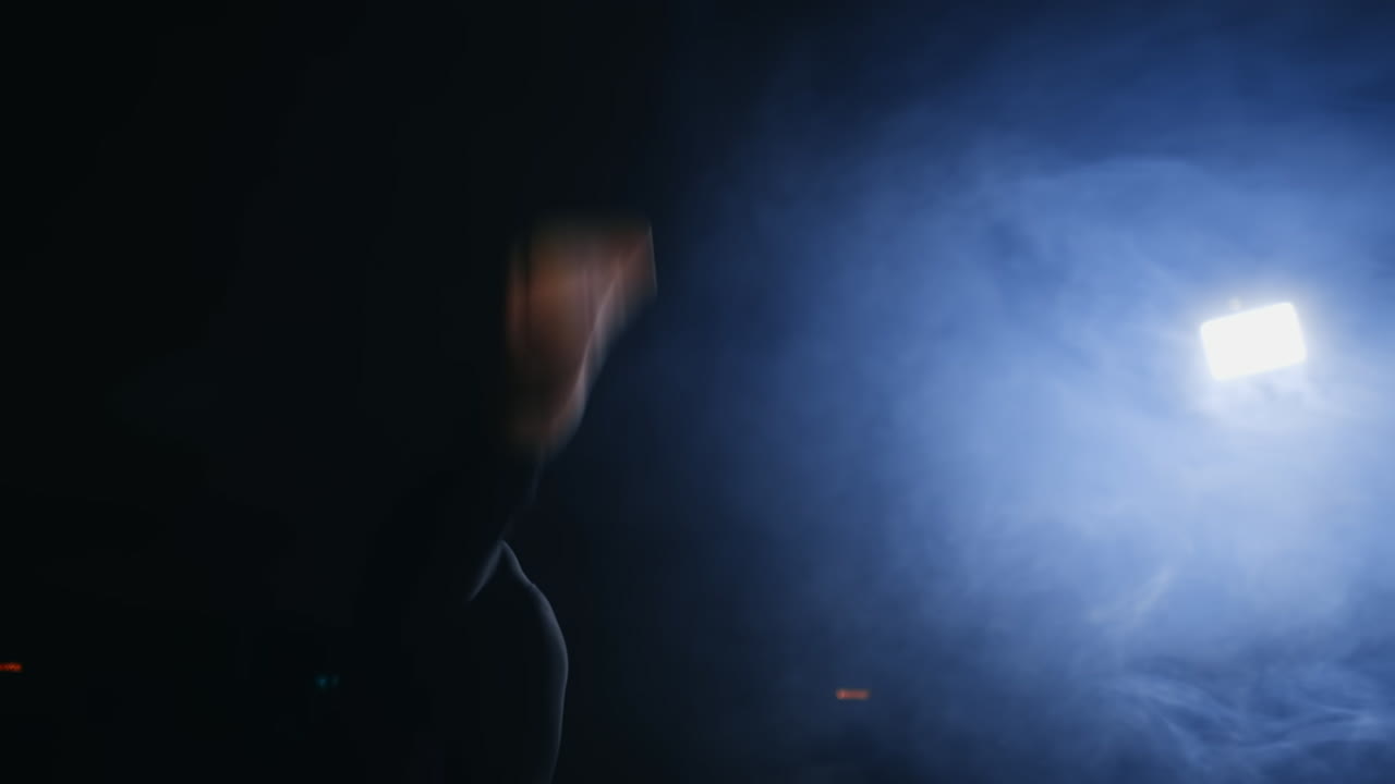 Girl gymnast performs flips on the gymnastics carpet in slow motion in the back light in the smoke