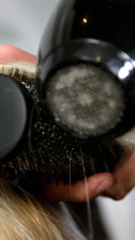 mujer secándose el cabello con un secador de pelo