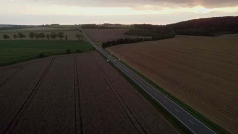 Luftaufnahme-Von-Autos,-Die-Auf-Einer-Ländlichen-Asphaltstraße-Mit-Einer-Wunderschönen-Landschaft-Vorbeifahren