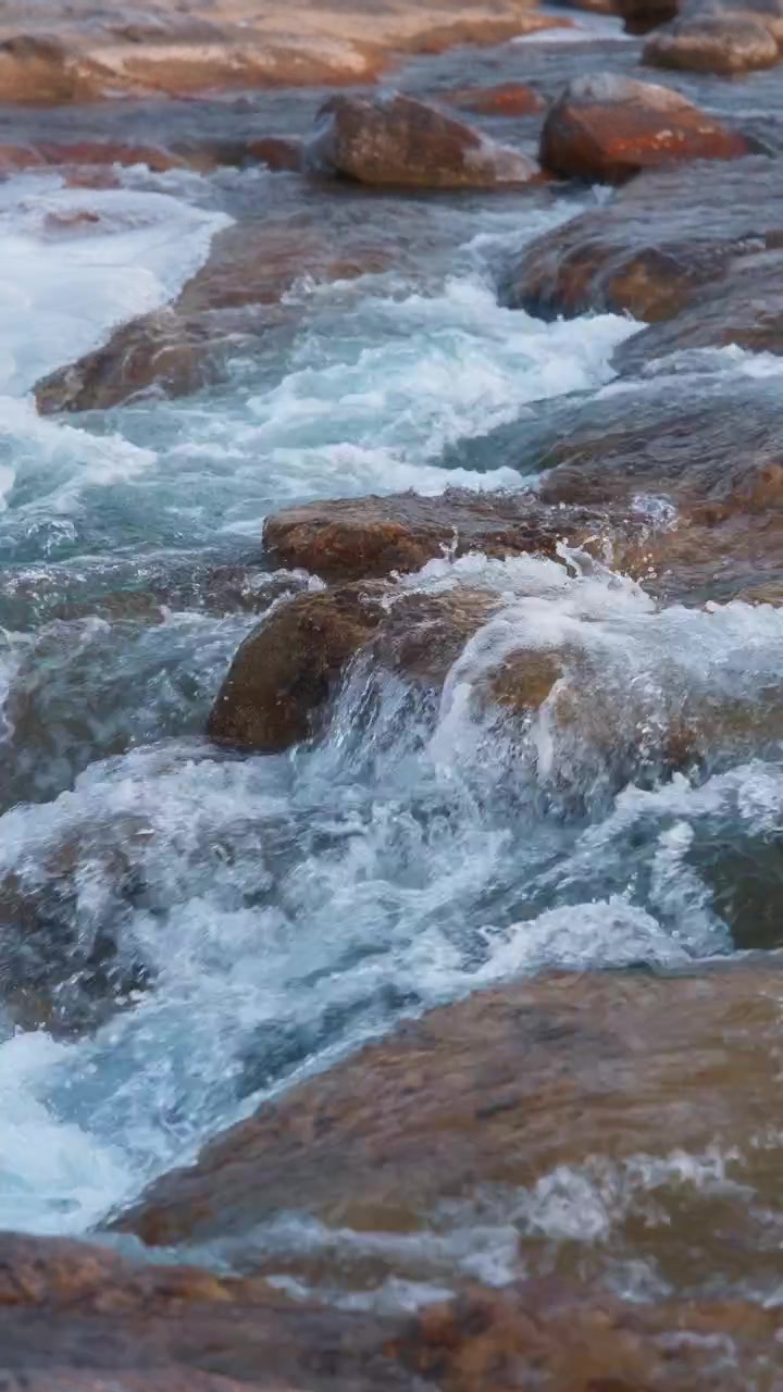 Flusso d'acqua che scorre sulle rocce. Movimento lento. Formato verticale.