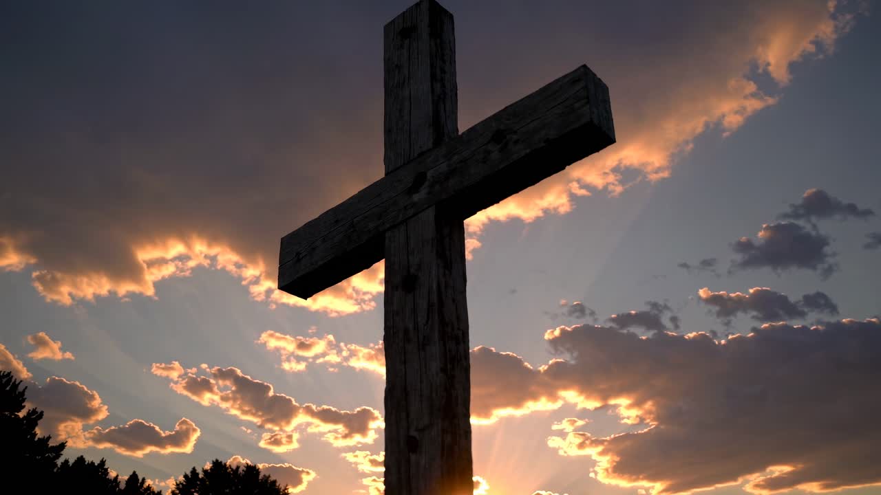A wooden cross silhouetted against a dramatic sunset sky, captured from a low angle