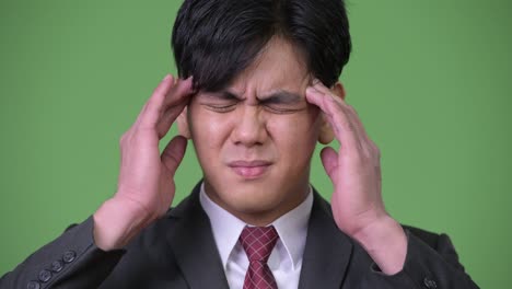 stressed young handsome asian businessman having headache