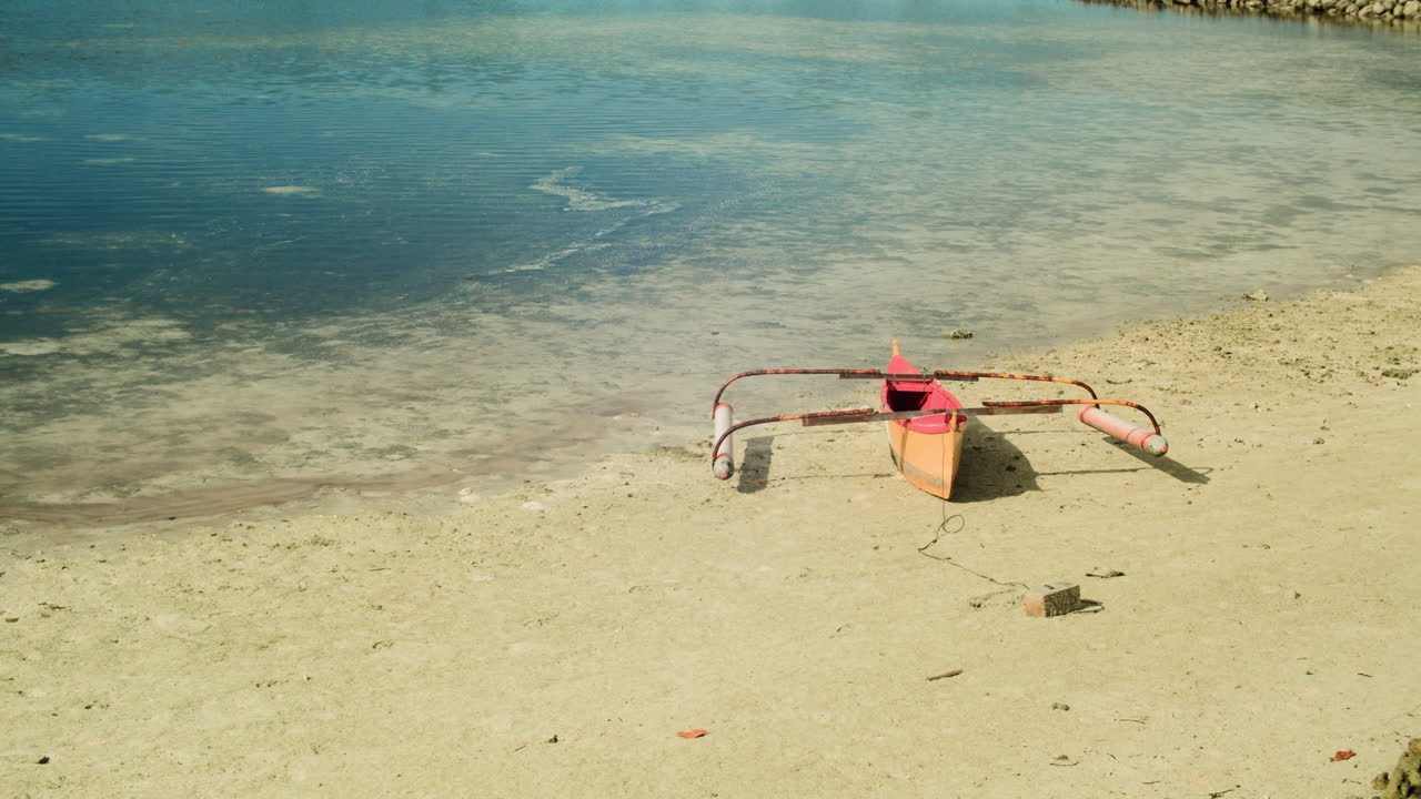 Small boat docked on white sands of Secret Beach in Siargao island, Philippines.