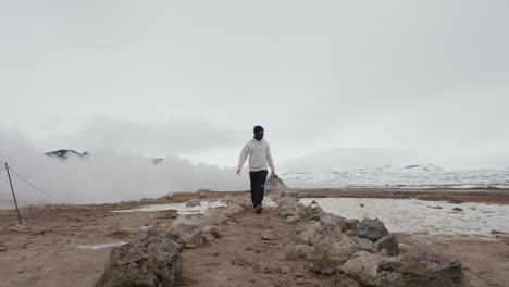 Tourist-walk-toward-among-rock-formation-at-Myvatn-Geothermal-Area,-Iceland